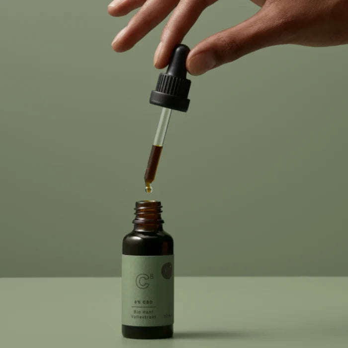 BioBloom Bio CBD Öl 8% in der 30-ml-Flasche, Hand hält die Pipette mit einem Tropfen Öl über der geöffneten Flasche