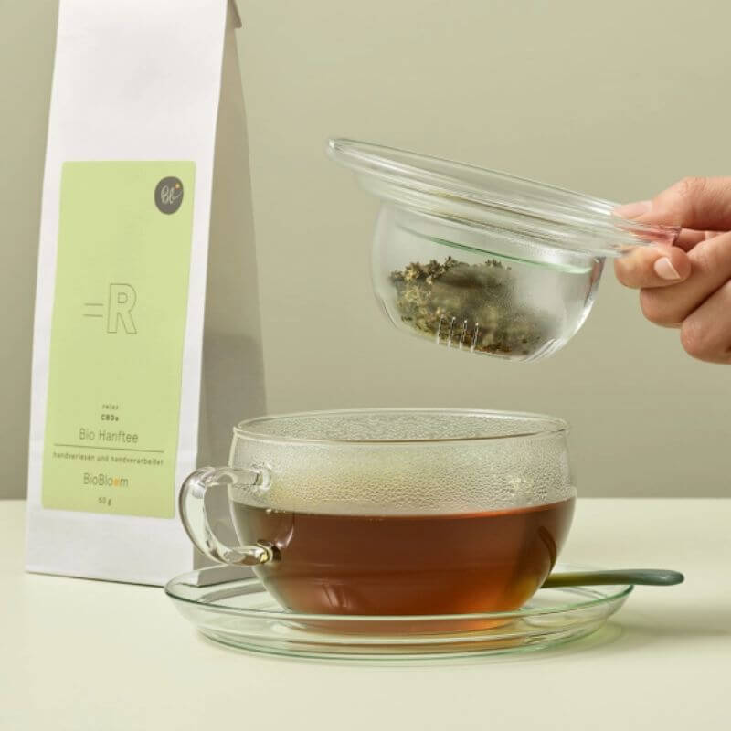 BioBloom Hanftee in Anwendung mit Teesieb und Teetasse