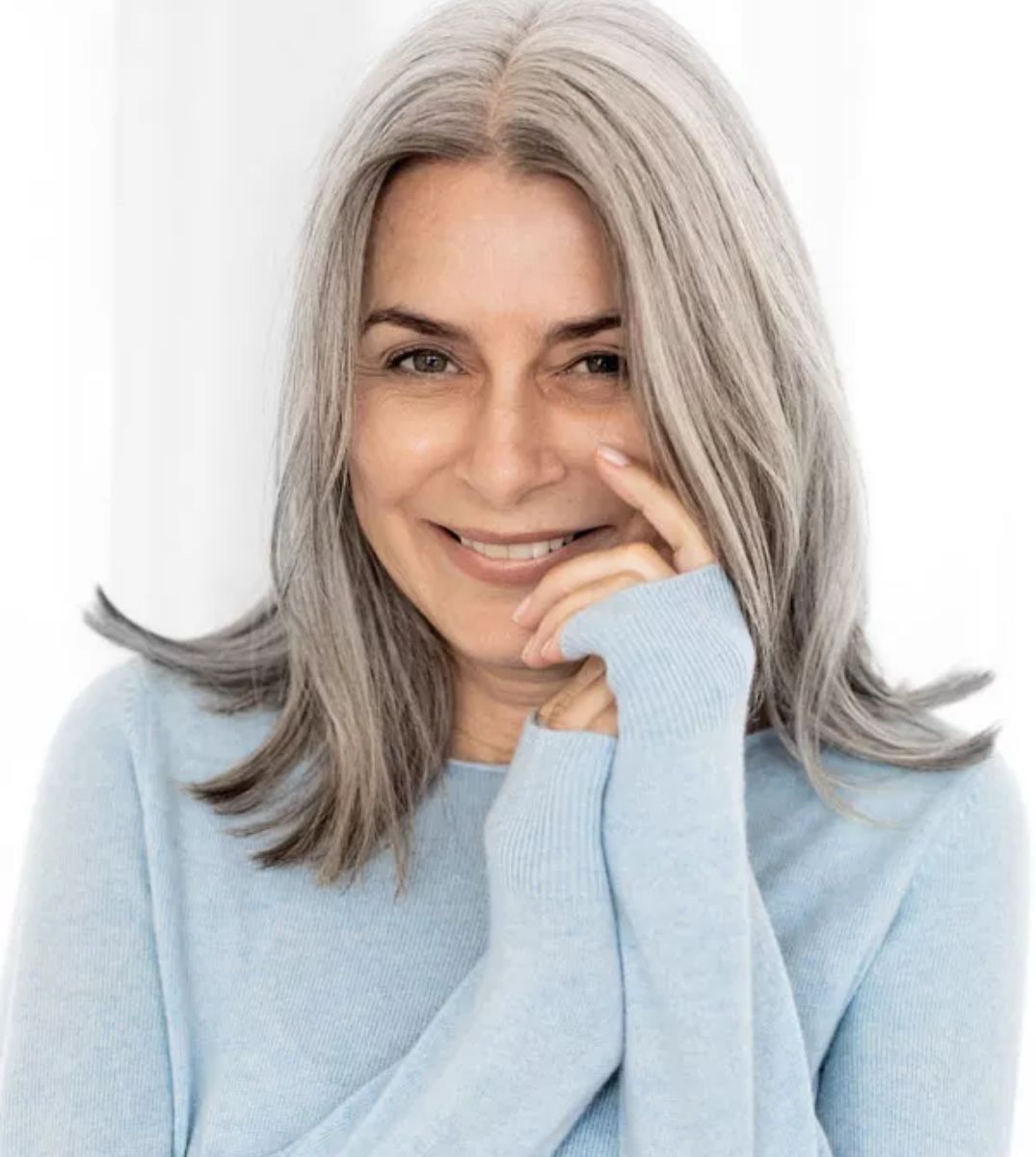 Porträt einer lächelnden Frau mit grauen Haaren und blauem Pullover