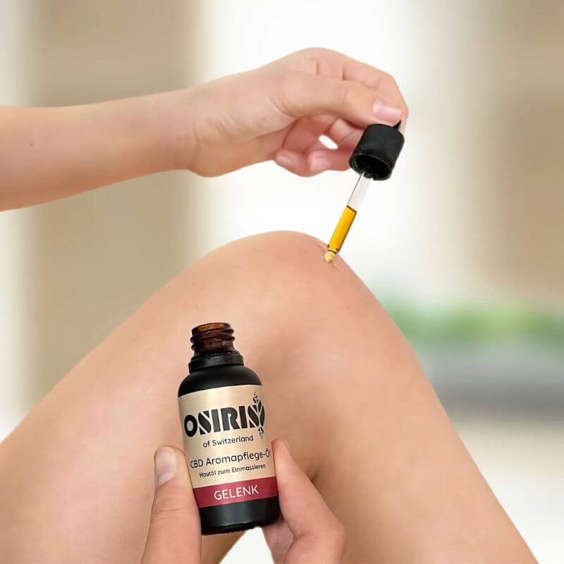 CBD Aromapflege Öl von Osiris in Anwendung am Knie inszeniert 