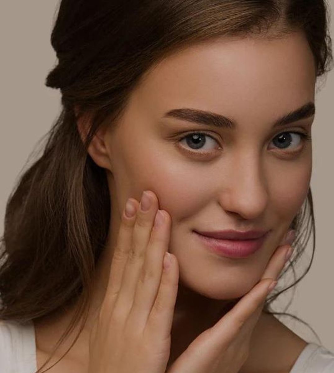 Porträt einer jungen Frau mit reiner Haut, die sanft ihr Gesicht berührt, symbolisch für die Vorteile von CBD-Kosmetikprodukten für die Schönheitspflege
